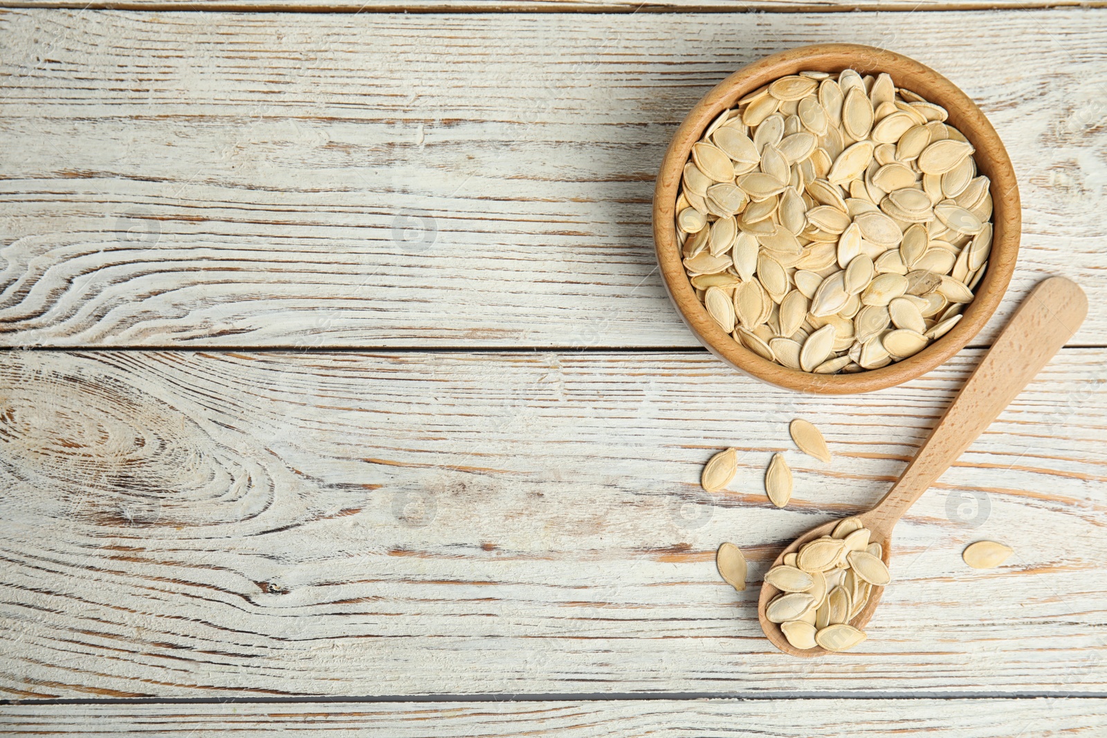 Photo of Raw pumpkin seeds on white wooden table, flat lay. Space for text