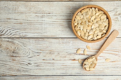 Photo of Raw pumpkin seeds on white wooden table, flat lay. Space for text