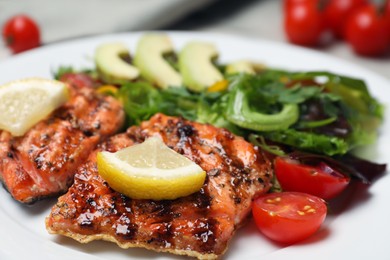 Photo of Tasty grilled salmon with lemon and tomatoes in plate, closeup