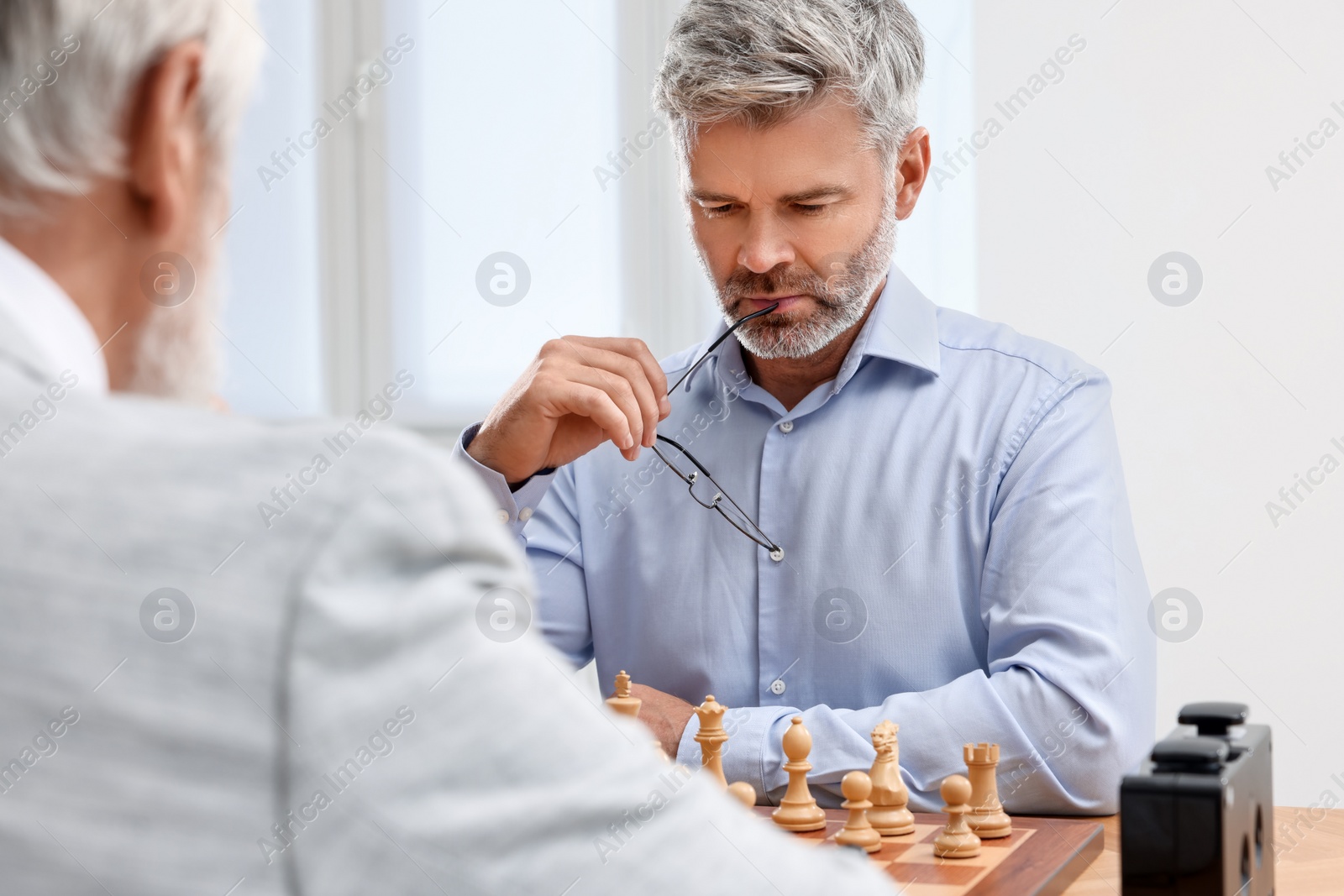 Photo of Men playing chess during tournament at table indoors