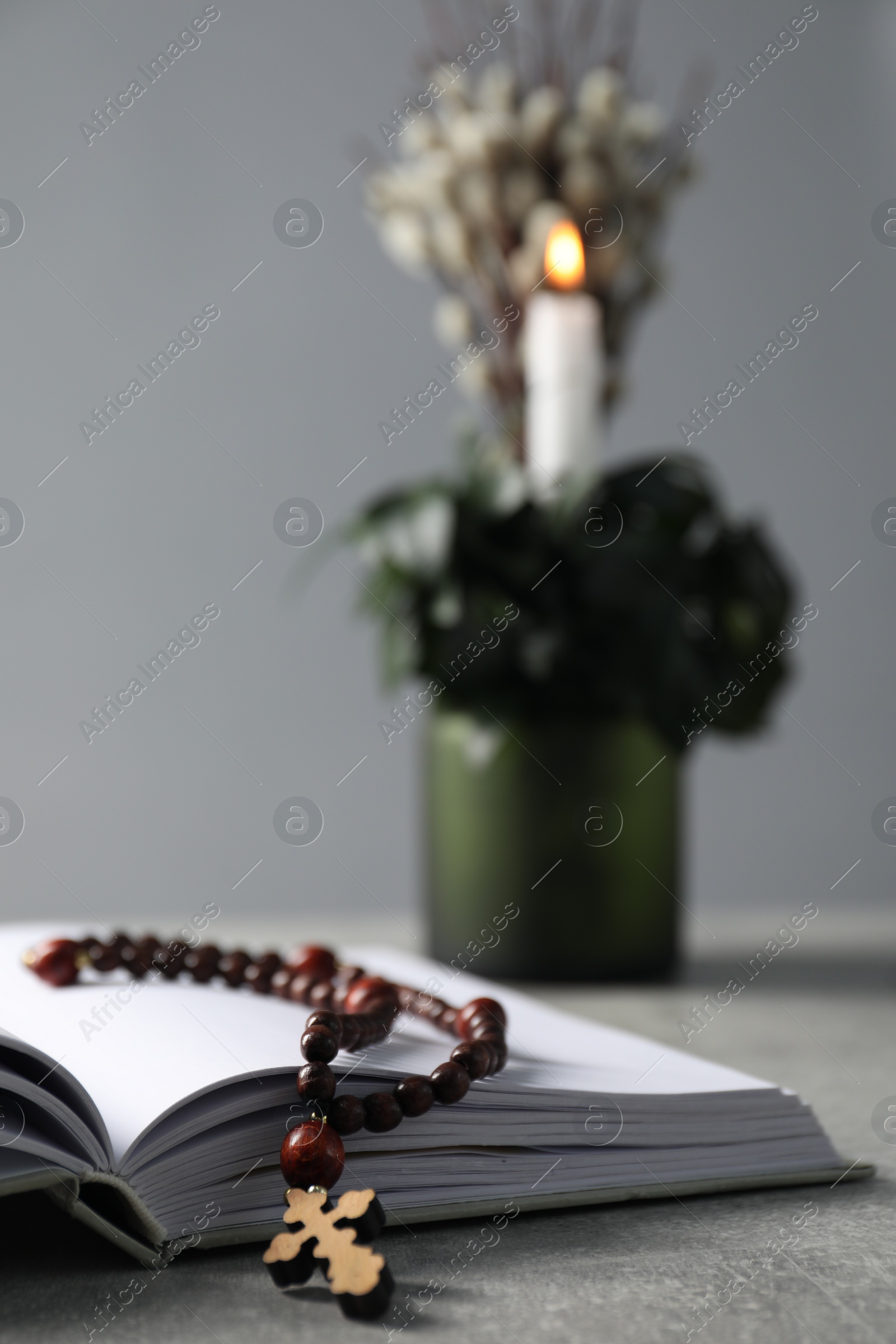 Photo of Bible and rosary beads on grey table, closeup