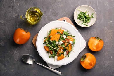 Photo of Delicious persimmon salad served on grey table, flat lay