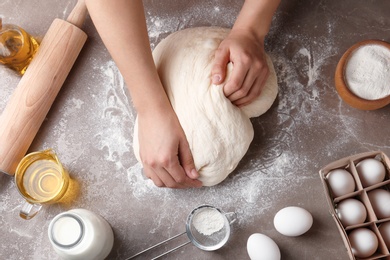 Female baker preparing bread dough at kitchen table, top view