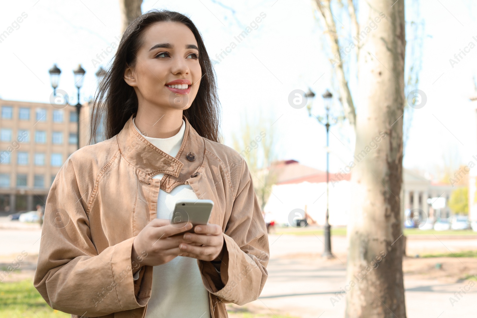 Photo of Young woman using phone outdoors on sunny day