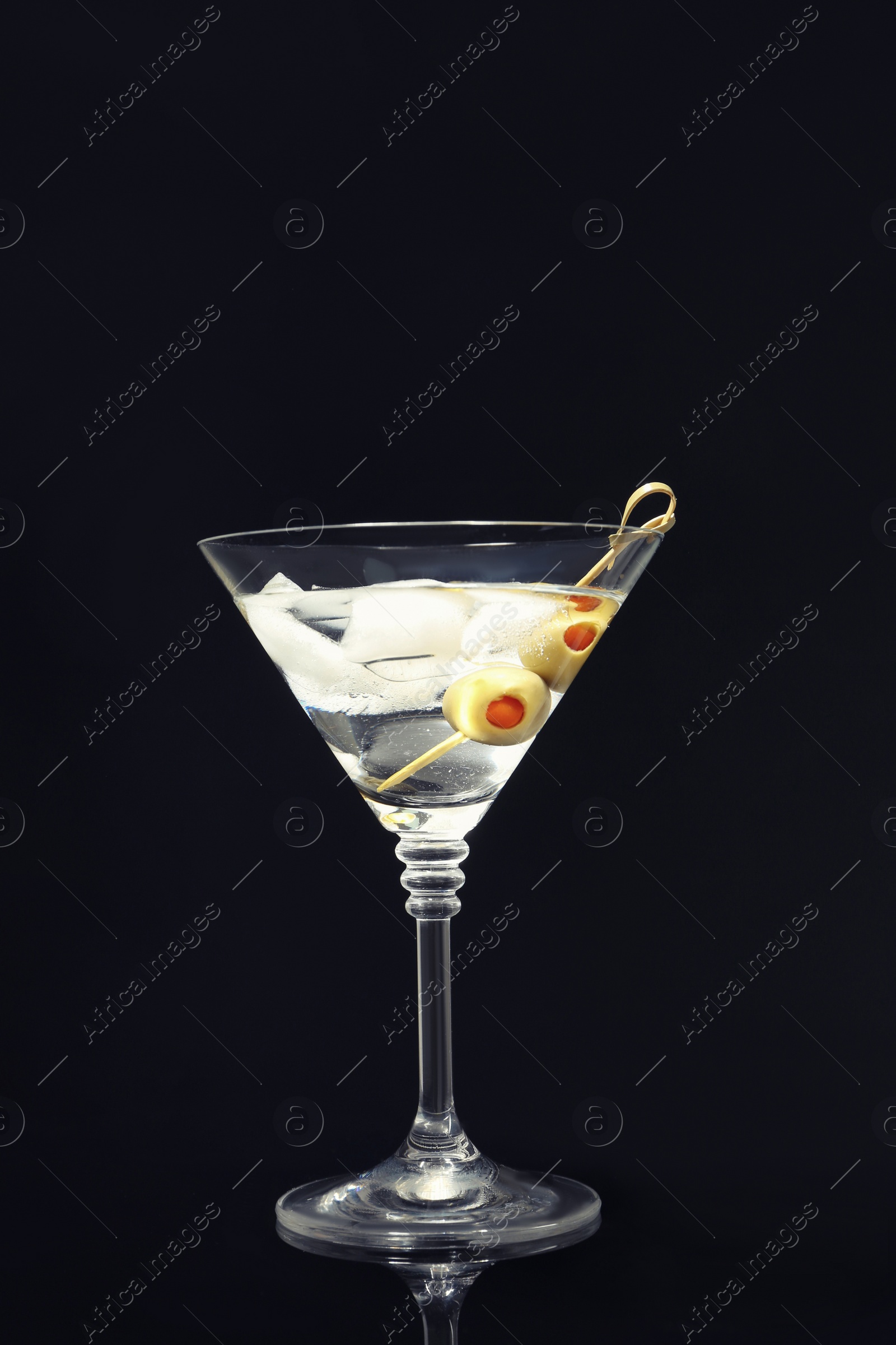 Photo of Martini cocktail with ice and olives on dark background