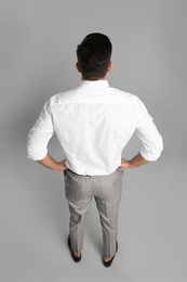 Businessman in formal clothes on grey background, back view