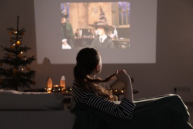 Photo of Lviv, Ukraine – January 24, 2023: Woman watching Harry Potter And The Philosopher’s Stone movie via video projector at home