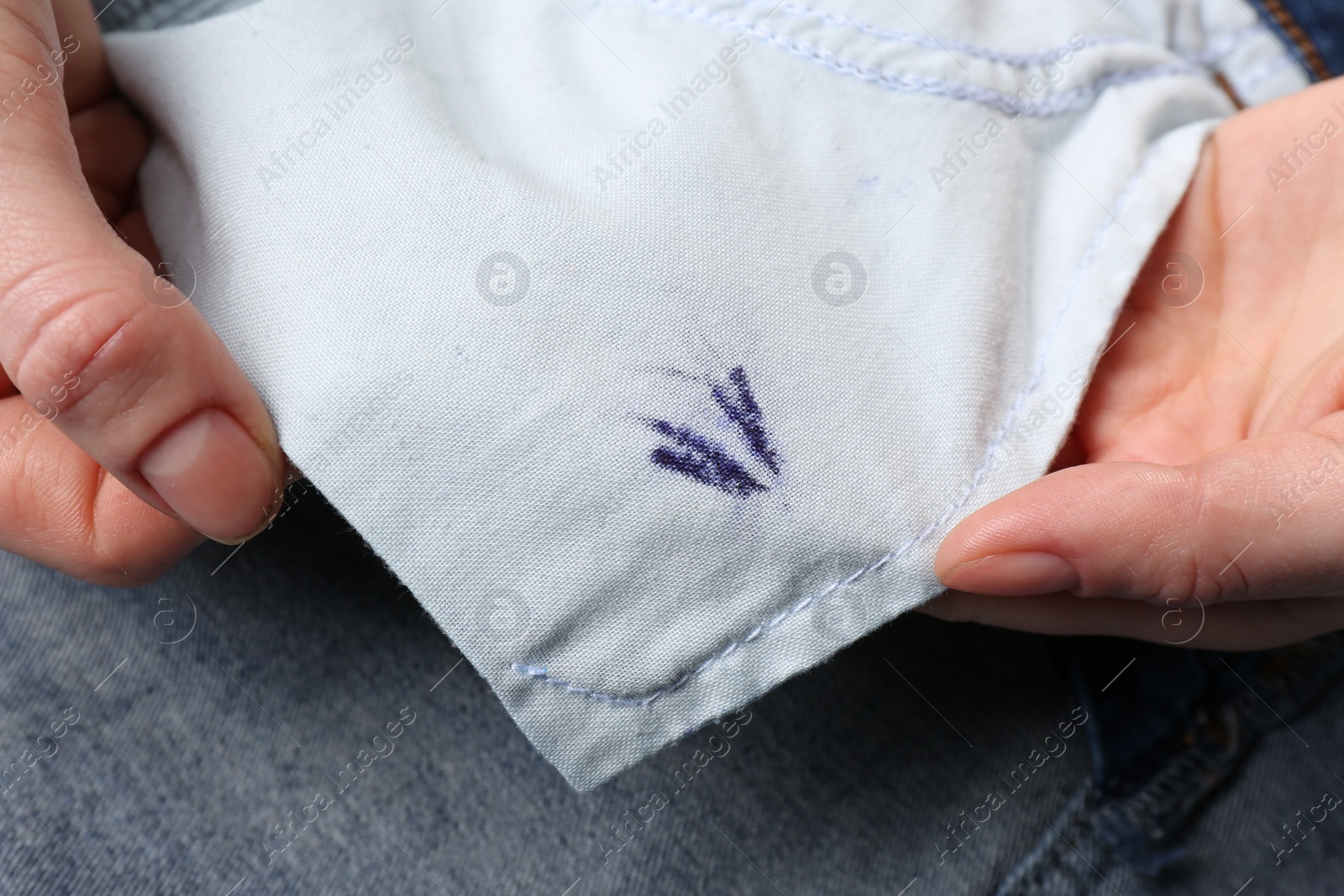 Photo of Woman holding jeans with ink stain, closeup