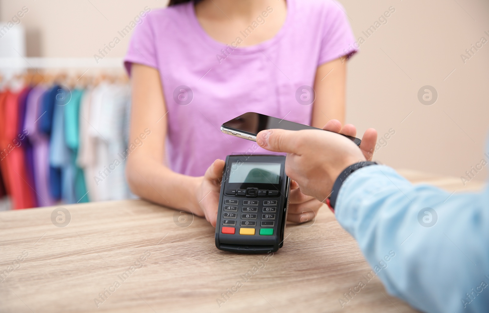 Photo of Man using terminal for contactless payment with smartphone in shop, closeup