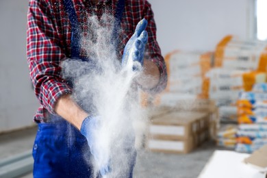 Photo of Construction worker shaking off dust from hands in room prepared for renovation, closeup