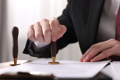 Photo of Notary stamping document at table in office, closeup