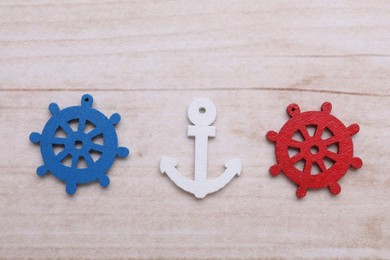 Anchor and ship wheel figures on wooden table, flat lay