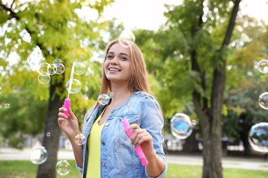 Young woman blowing soap bubbles in park