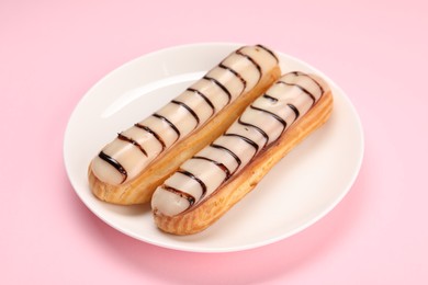 Photo of Delicious eclairs covered with glaze on pink background