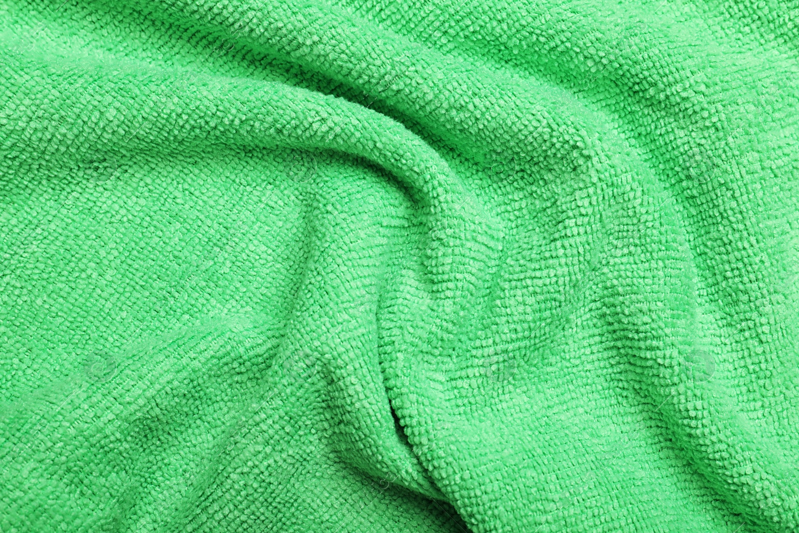 Photo of Crumpled light green microfiber cloth as background, closeup