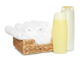 Photo of Wicker basket with folded soft terry towels and cosmetic products on white background