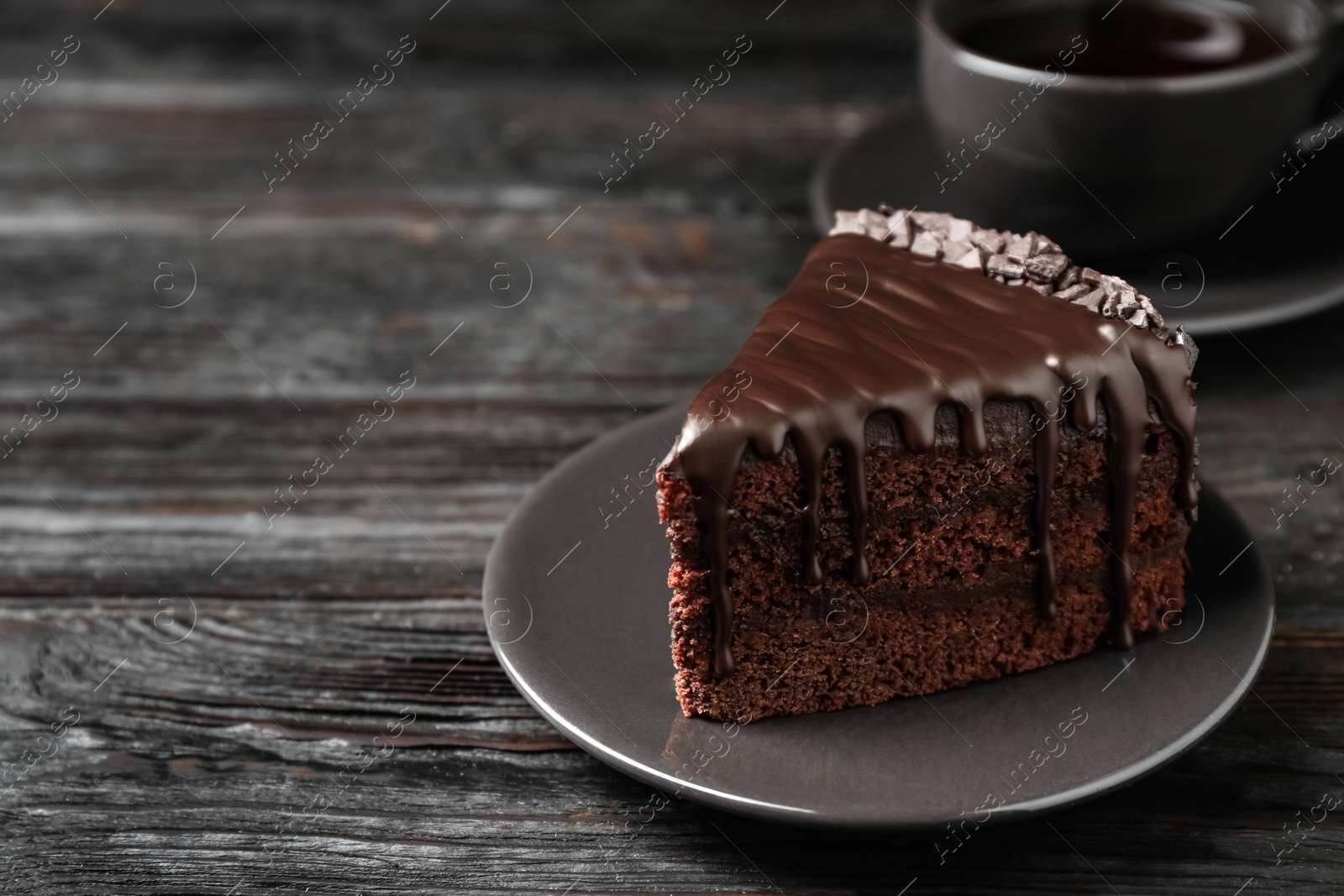 Photo of Delicious chocolate cake on black wooden table, space for text