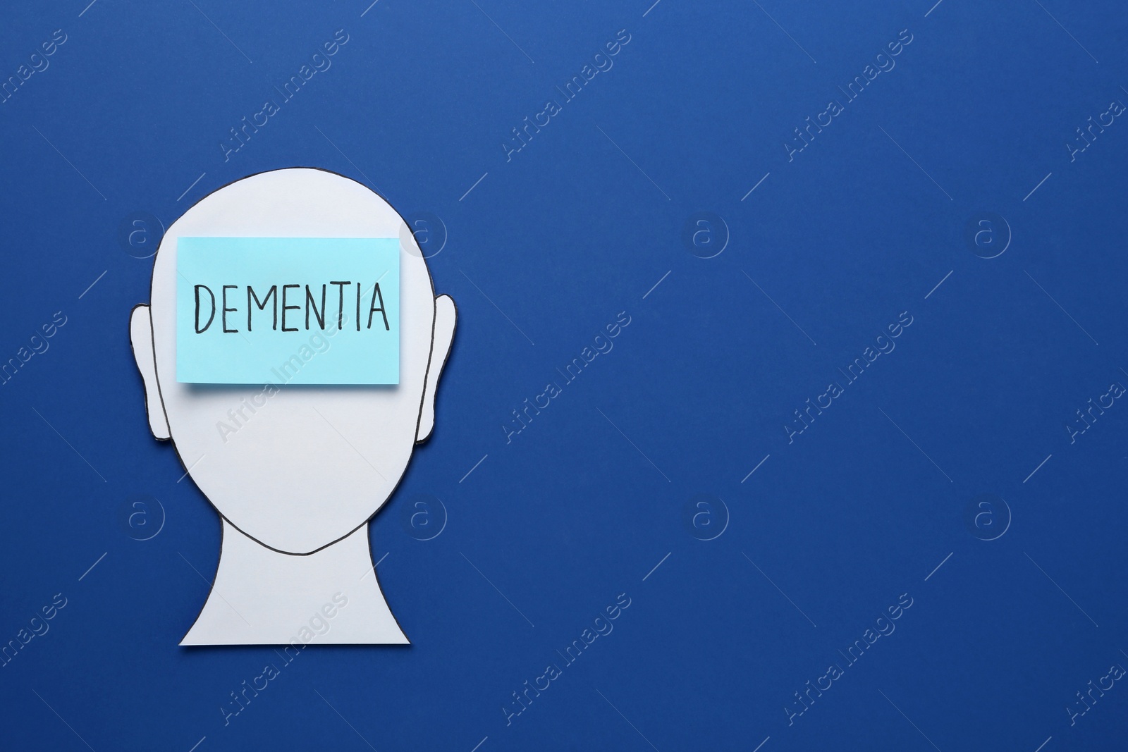 Photo of Human head paper cutout and note with word Dementia on blue background, top view. Space for text