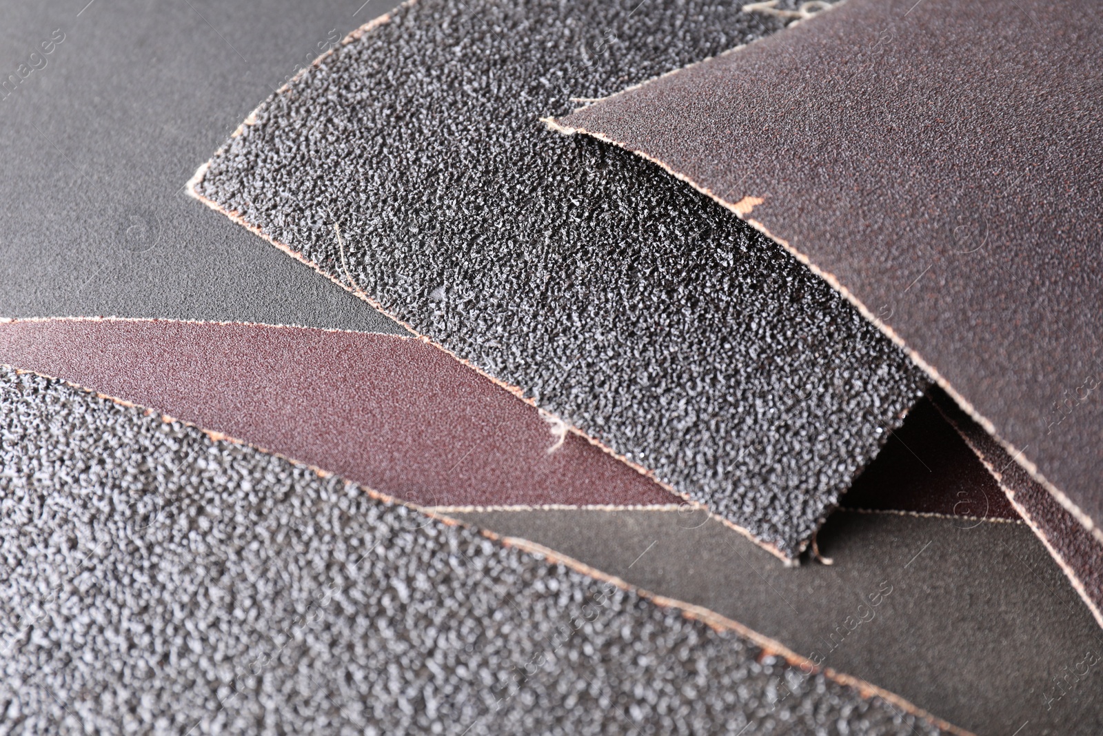 Photo of Many sheets of sandpaper as background, closeup