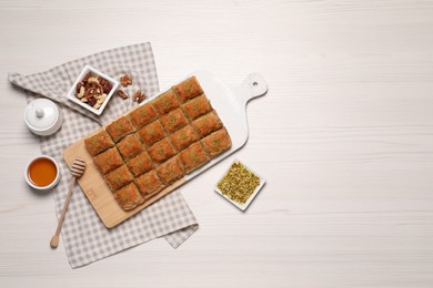 Photo of Delicious sweet baklava served on white wooden table, flat lay. Space for text