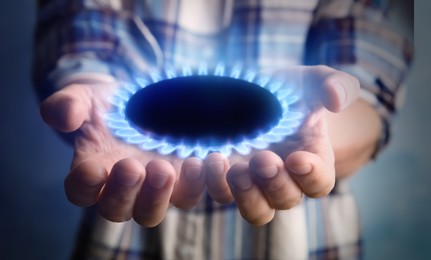 Image of Closeup view of man holding gas burner with blue flame