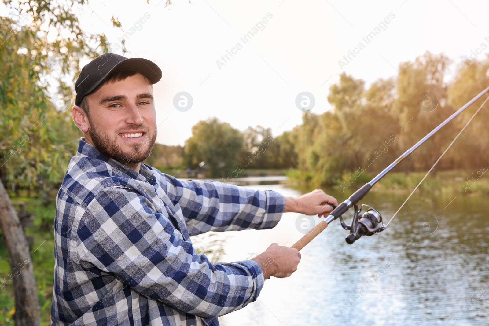 Photo of Man with rod fishing at riverside. Recreational activity