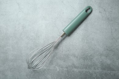 Metal whisk on gray table, top view