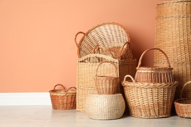 Photo of Many different wicker baskets on floor near coral wall. Space for text