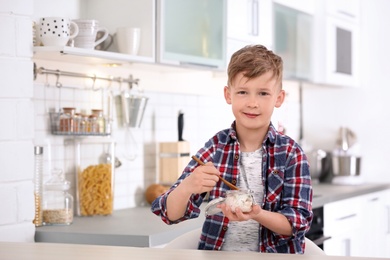 Photo of Little boy with yogurt in kitchen