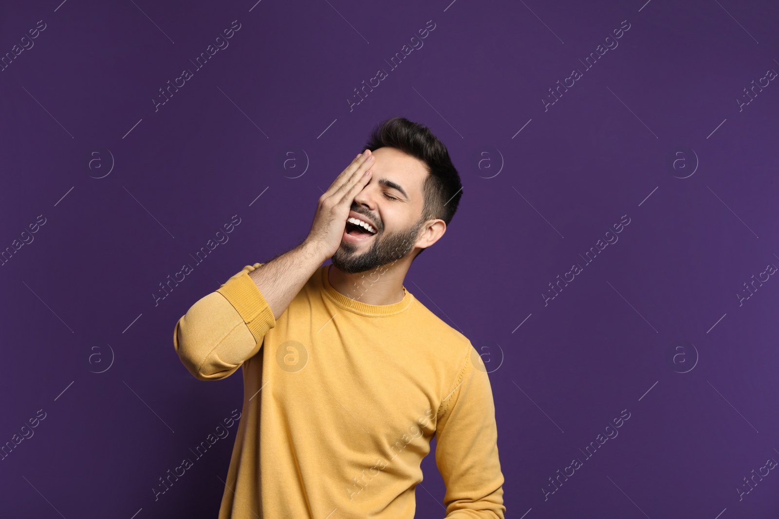 Photo of Young man laughing on purple background. Funny joke