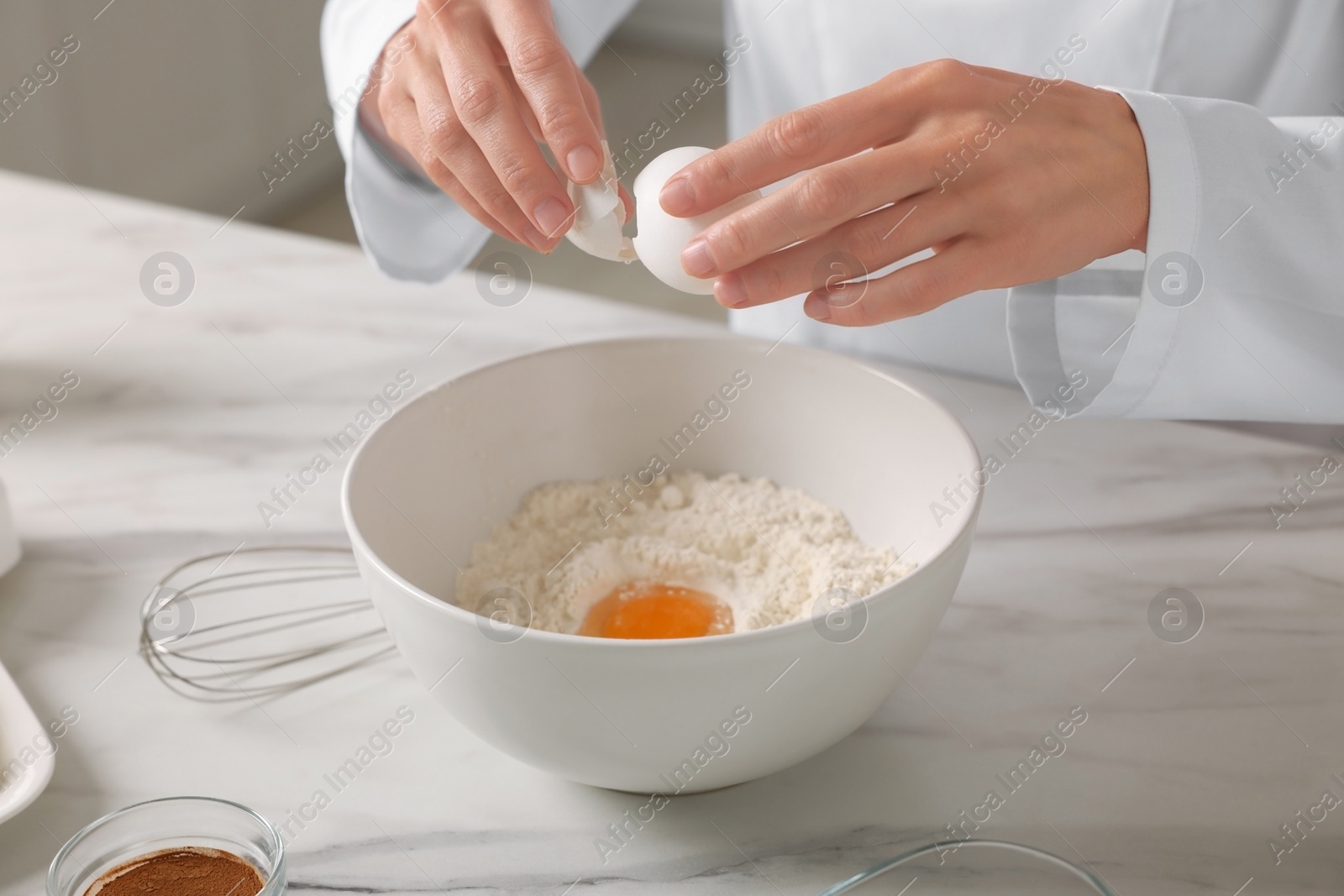 Photo of Professional chef making dough at white marble table indoors, closeup