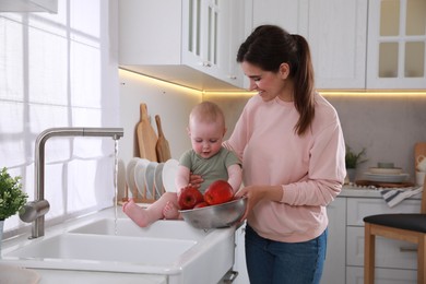 Mother and her cute little baby spending time together in kitchen