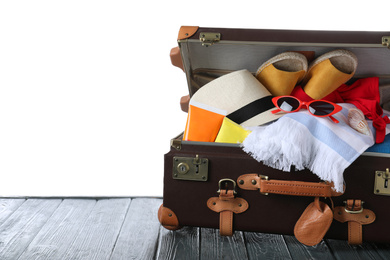 Photo of Open vintage suitcase with different beach objects on grey wooden table against white background. Space for text