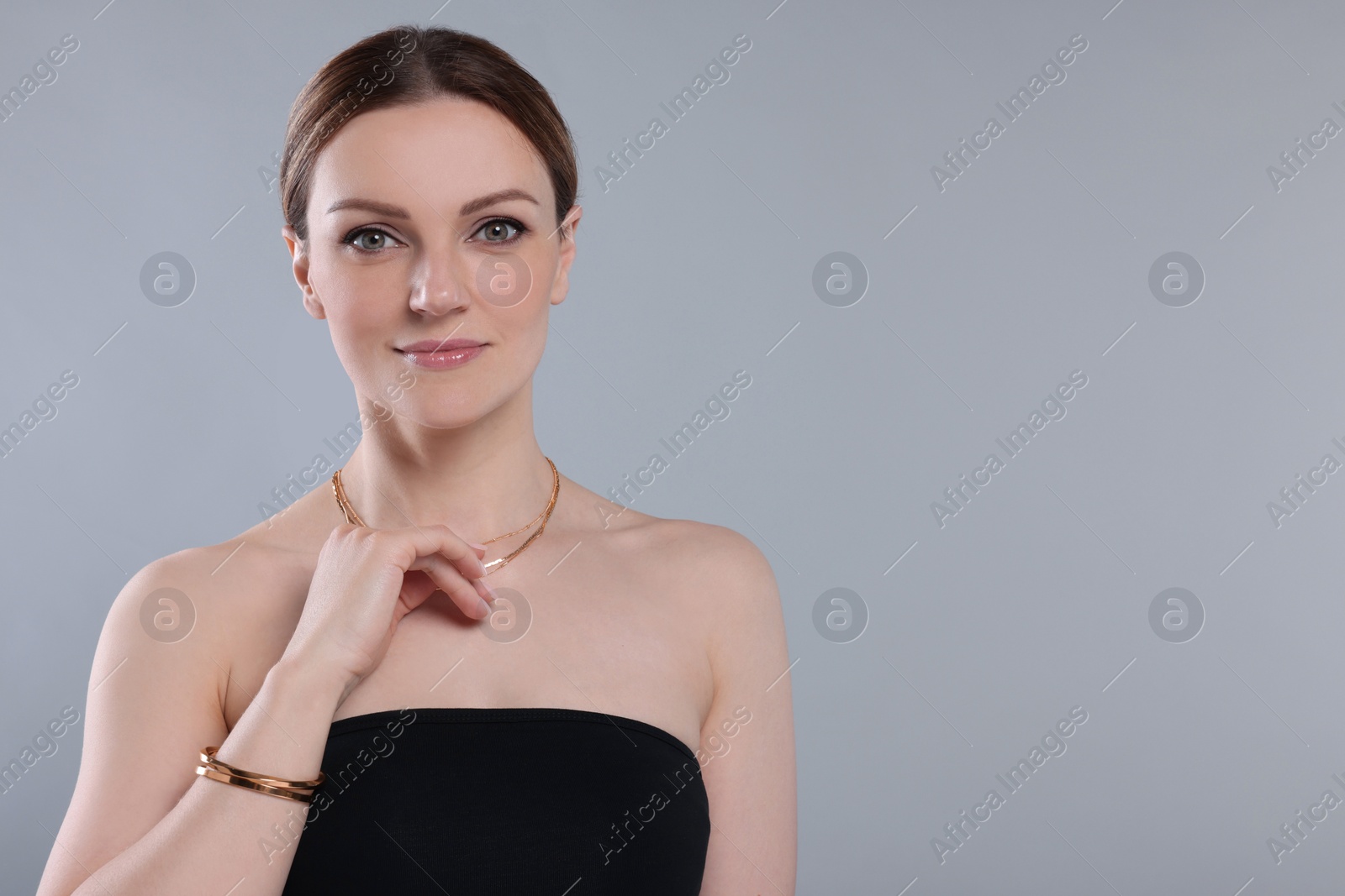 Photo of Beautiful woman with elegant jewelry on light grey background. Space for text