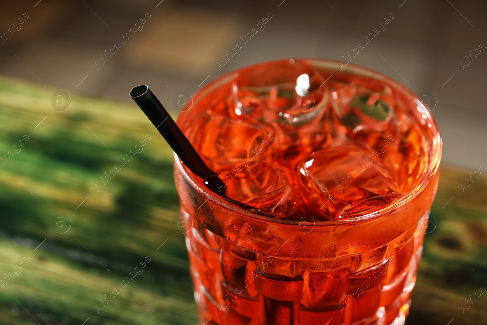 Photo of Glass of delicious cocktail with ice on table, closeup