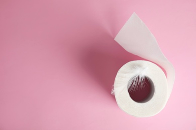 Toilet paper roll with feather on color background, top view. Space for text
