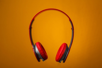 Photo of Wireless headphones with earmuffs on color background