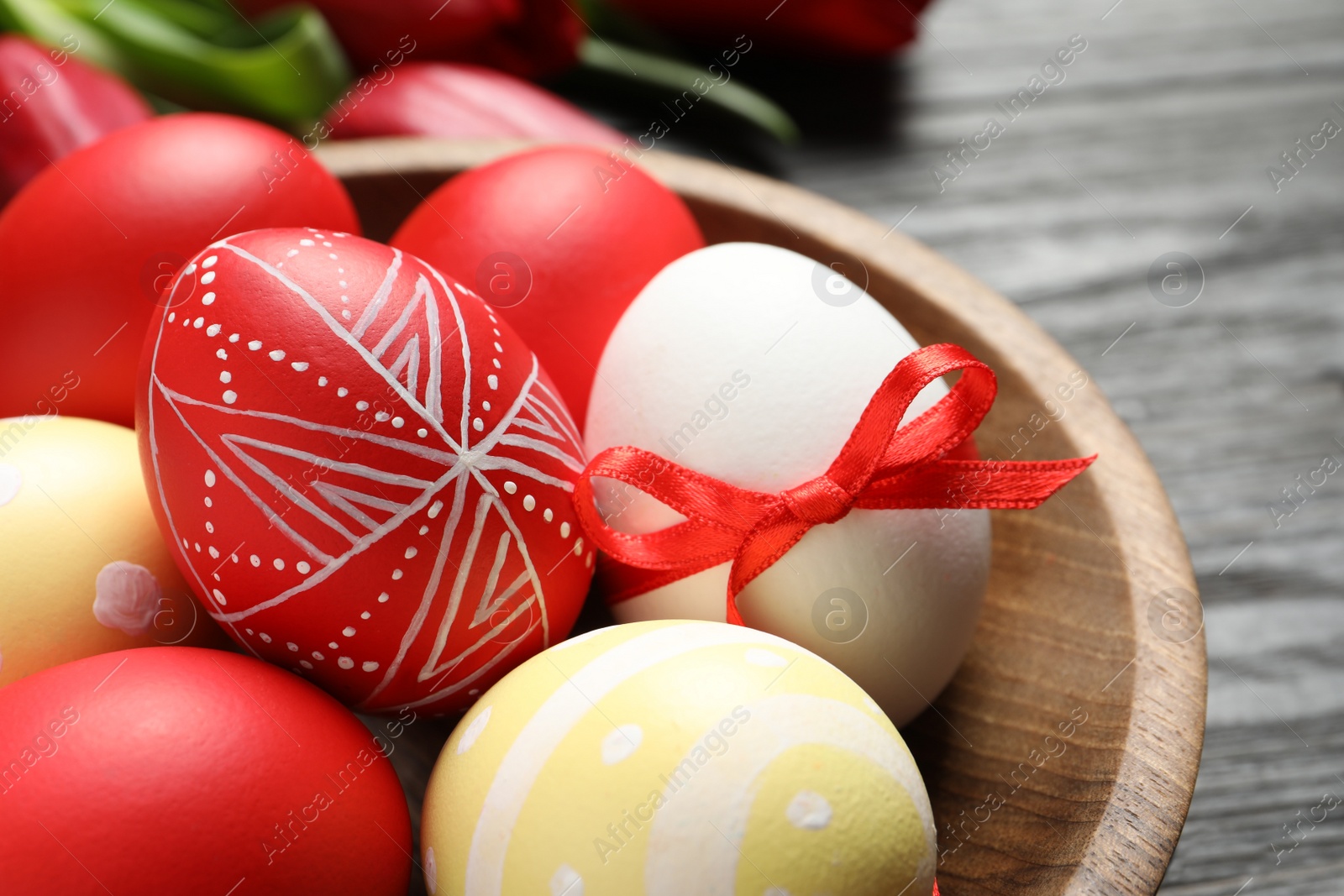 Photo of Bowl with painted Easter eggs on table, closeup