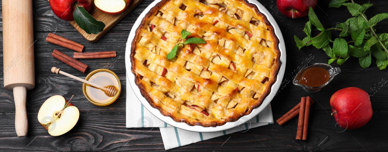 Image of Flat lay composition with fresh traditional apple pie on black wooden table. Banner design