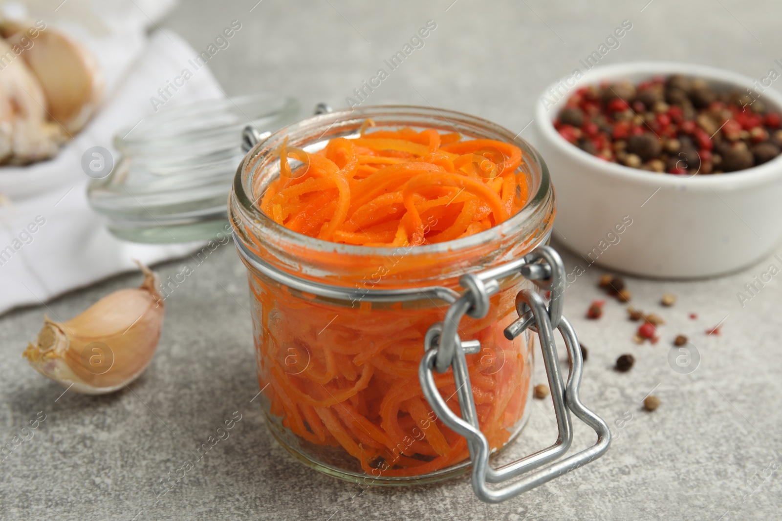 Photo of Delicious Korean carrot salad in glass jar on grey table