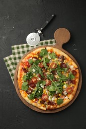 Photo of Delicious vegetarian pizza and cutter on black table, top view