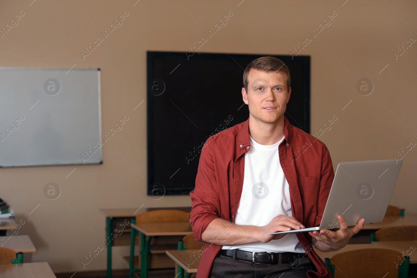 Photo of Portrait of male teacher with laptop in modern classroom
