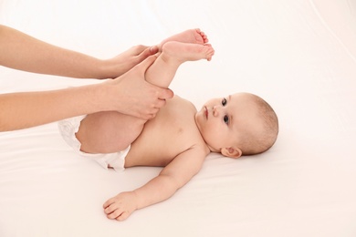 Photo of Mother and her cute child on white bed. Baby massage and exercises