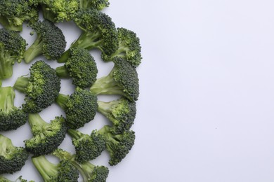 Many fresh green broccoli pieces on white background, flat lay. Space for text