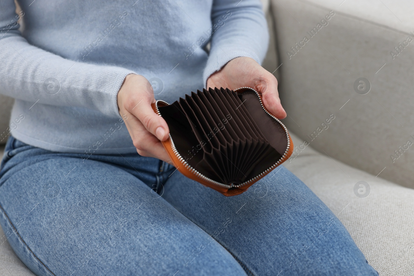 Photo of Woman with empty wallet on sofa indoors, closeup