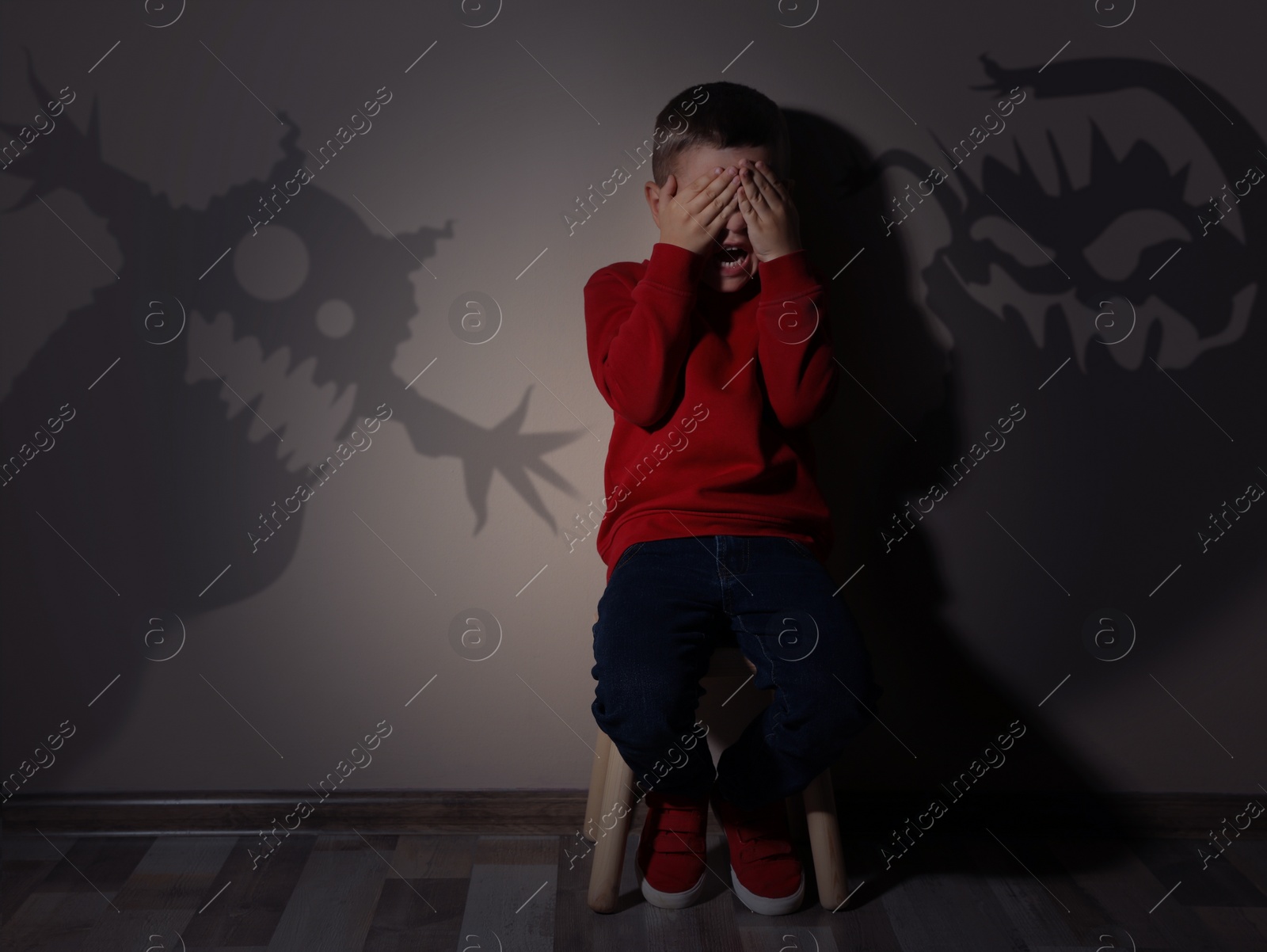 Image of Shadows of monsters on wall and scared little boy in room