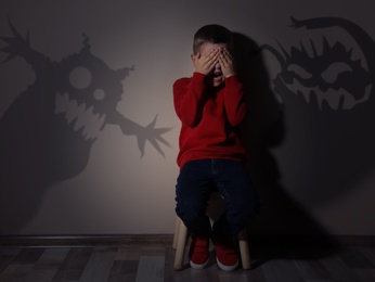 Image of Shadows of monsters on wall and scared little boy in room