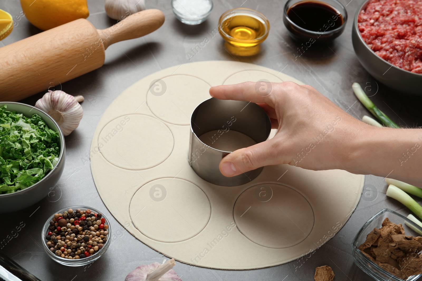 Photo of Woman cooking delicious gyoza at light grey table, closeup