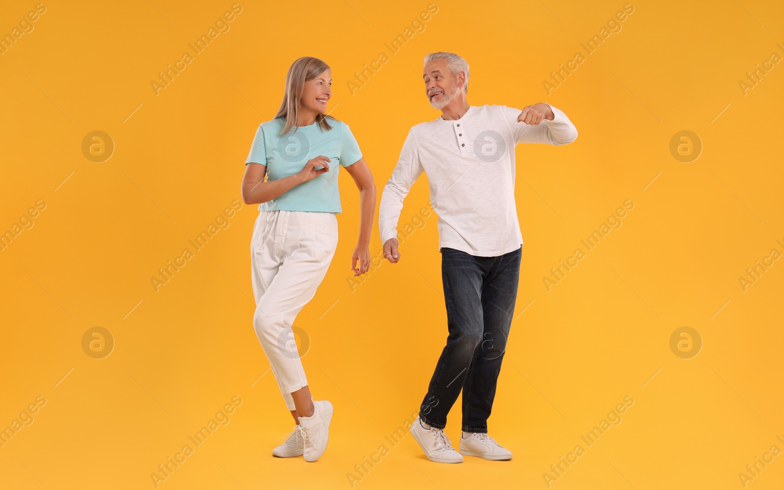 Photo of Senior couple dancing together on orange background