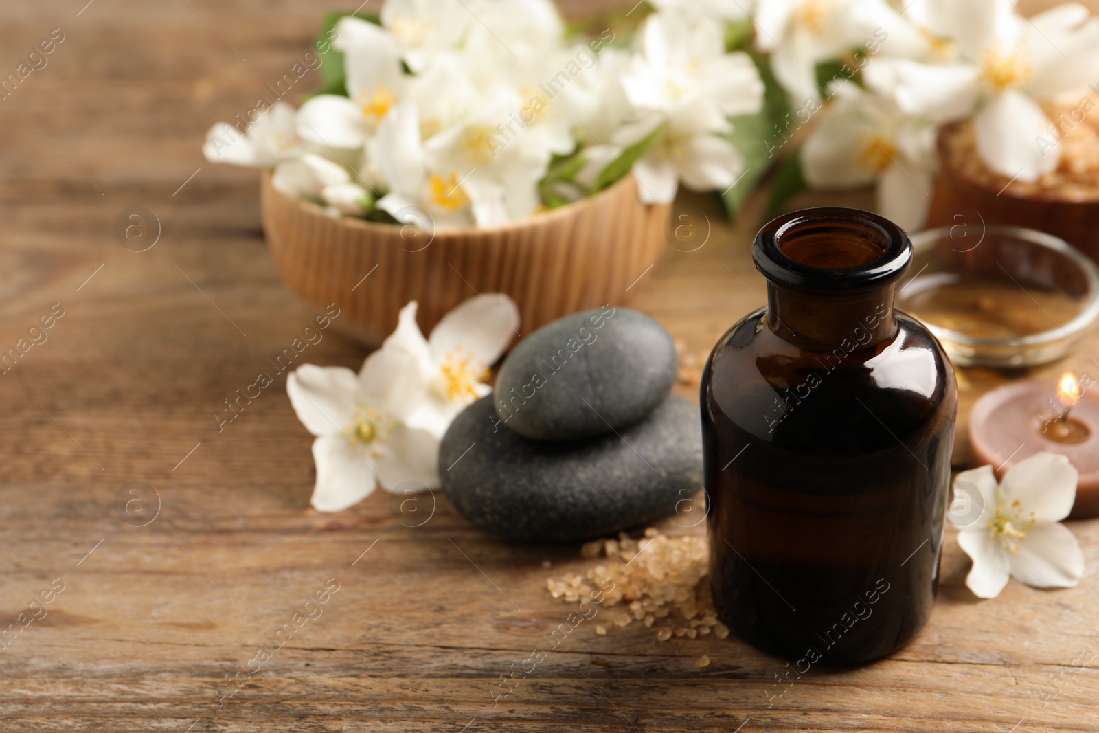 Photo of Beautiful composition with jasmine essential oil and fresh flowers on wooden table. Space for text